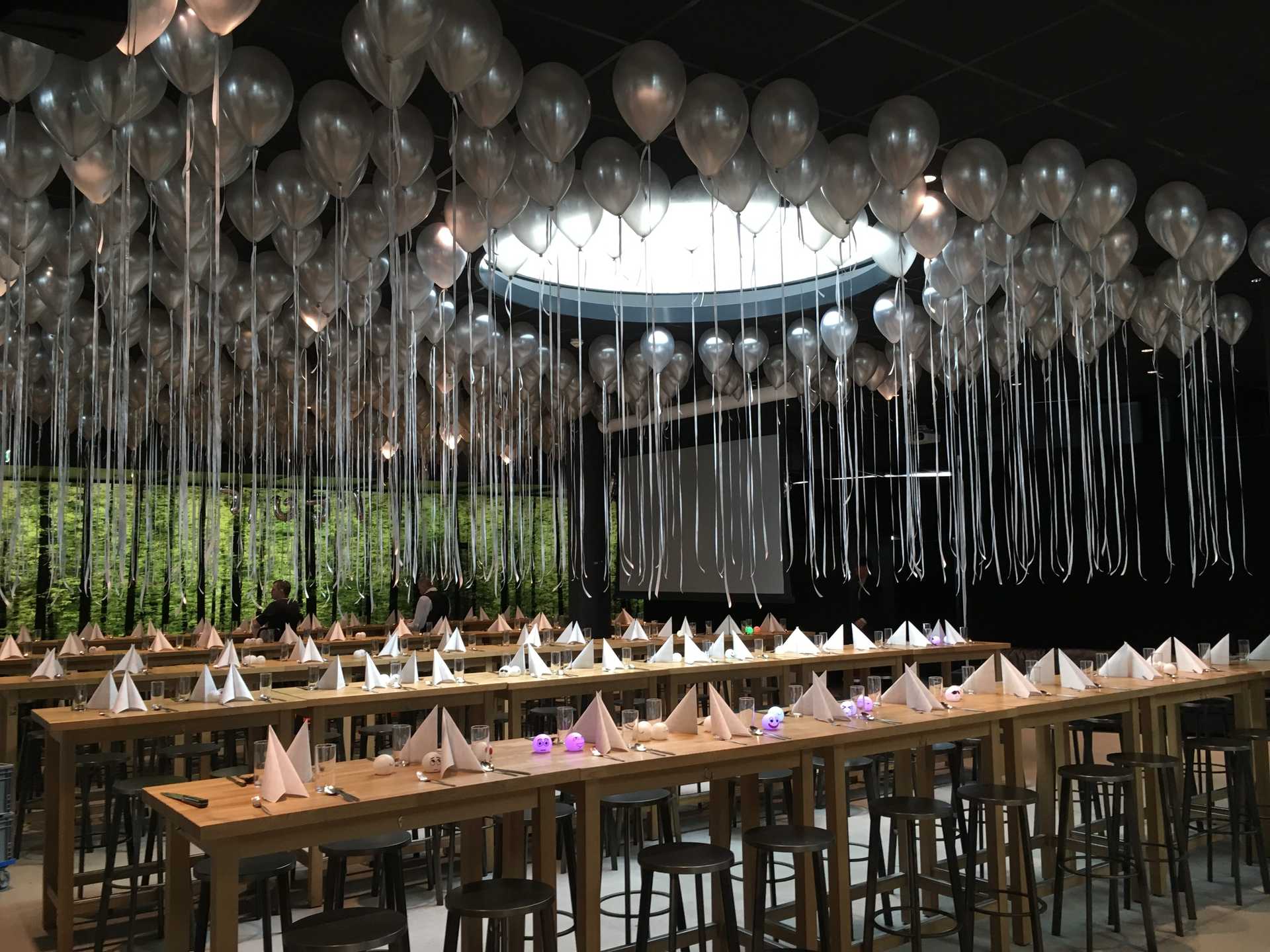 Tische mit silbernen und weißen Tischdecken und Ballons von der Decke in Wien