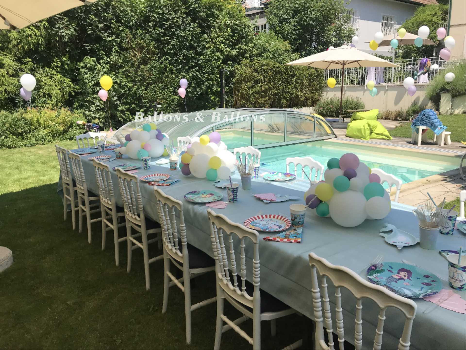 Ein langer Tisch mit Tischdecken, Stühlen und vielen Ballons.