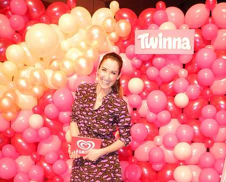 Eine Frau steht neben einer großen Anzahl von Ballons, Wand bedeckt mit Ballons.