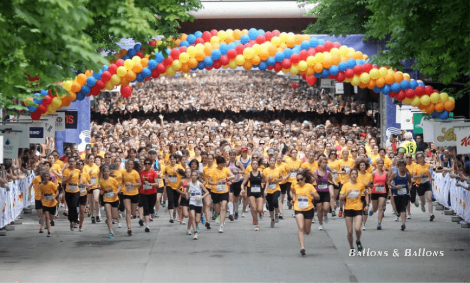 Eine Gruppe von Personen läuft unter Ballons die Straße entlang in Wien.