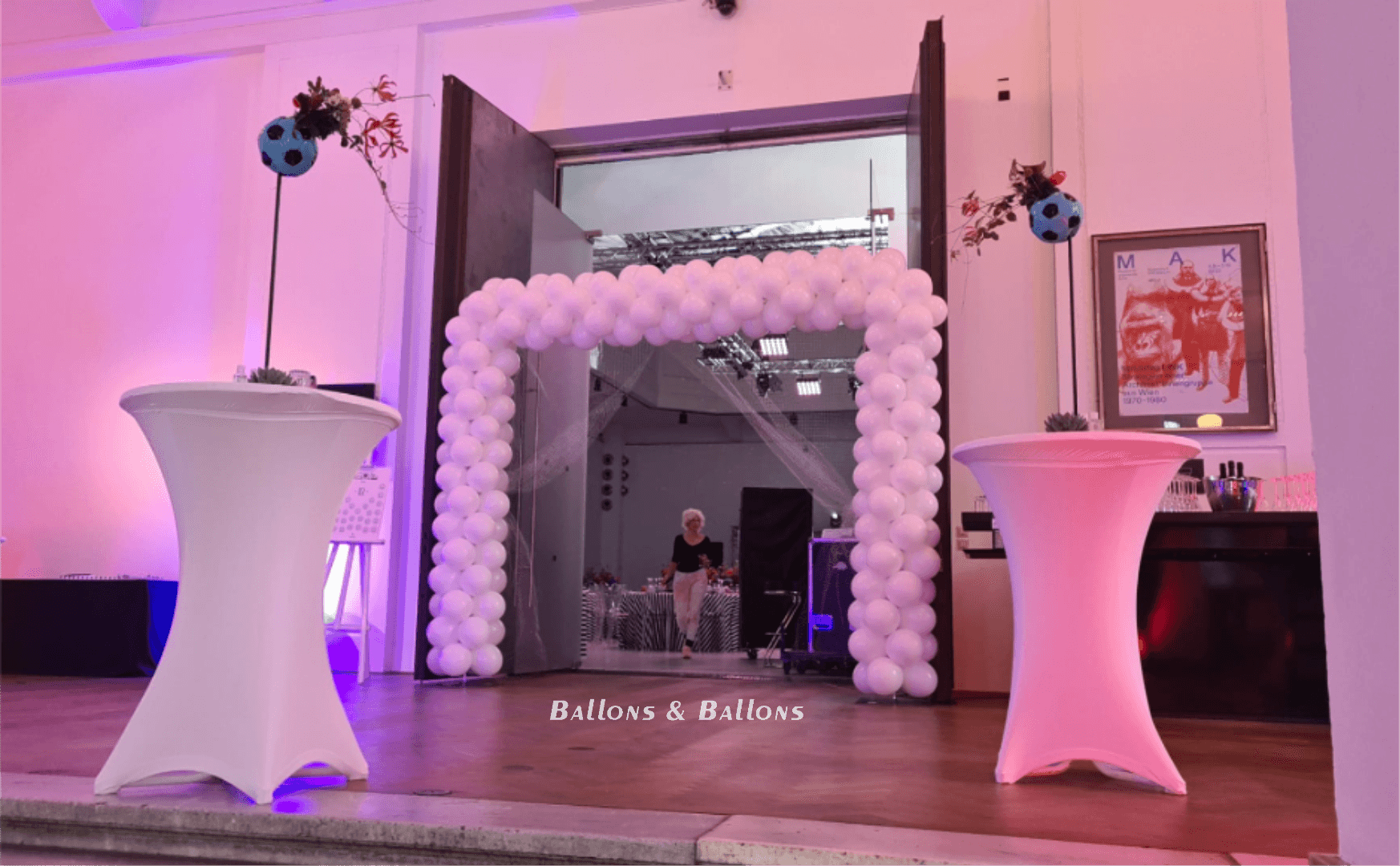 Ein Ballonbogen und dekorierte Tische in einem Raum in Wien.