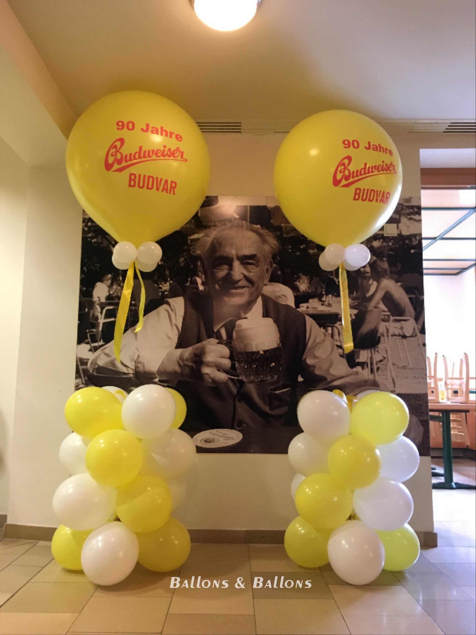 Eine Wand mit einem Poster eines buddhistischen Mannes und großen gelben Ballons in einem Flur in Wien.