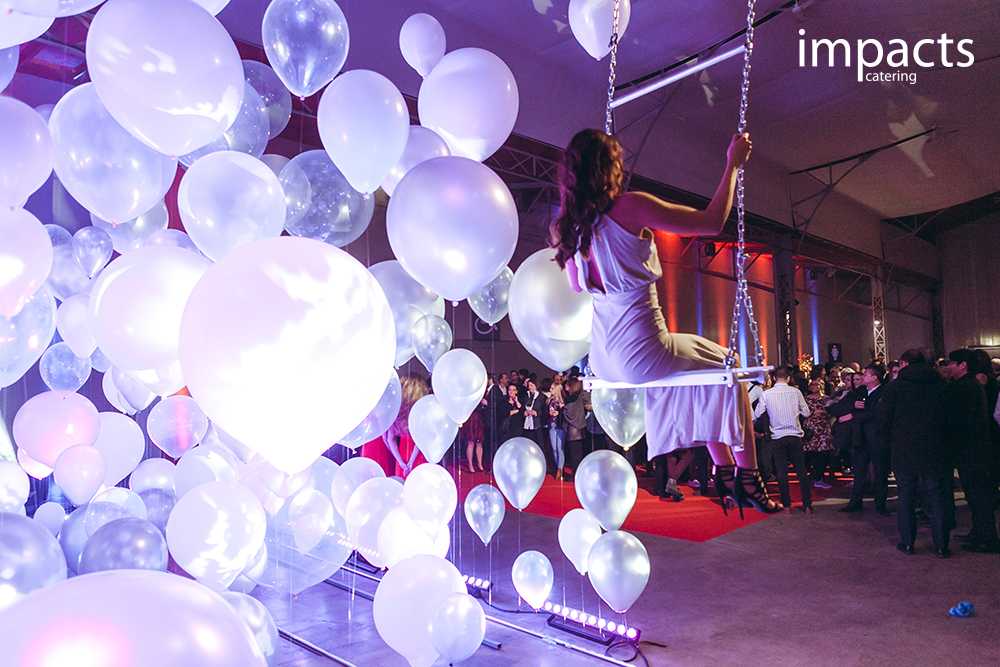 Eine Frau sitzt auf einer Schaukel zwischen Ballons und einer Menschenmenge in Wien.